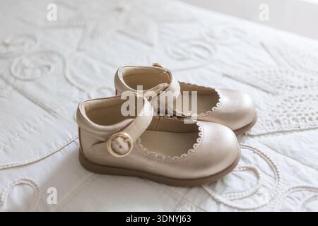 Soft gold baby girl dress shoes for baptism, wedding or special ceremony  lying on white lace bedspread indoors Stock Photo - Alamy
