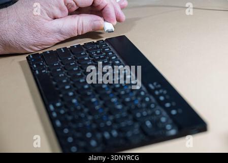 A person is plugging a USB cable into a keyboard for charging a portable keyboar wire free bluetooth. Stock Photo