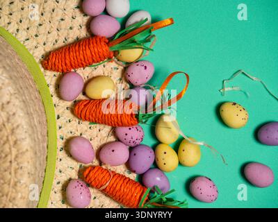 Easter bonnet straw hat decorated with eggs and flowers green background Stock Photo