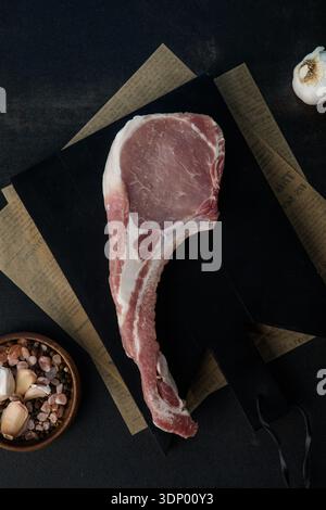 Fresh tomahawk raw steak. Dry aged raw tomahawk pork steak with herbs and salt on old wooden background. Preparing to grill. Stock Photo