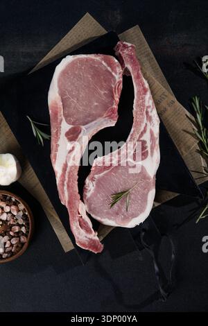Fresh tomahawk raw steak. Dry aged raw tomahawk pork steak with herbs and salt on old wooden background. Preparing to grill. Stock Photo