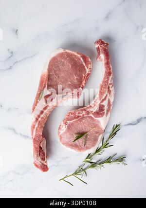 Fresh tomahawk raw steak. Dry aged raw tomahawk pork steak with herbs and salt on old wooden background. Preparing to grill. Stock Photo