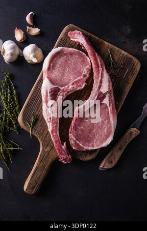 Fresh tomahawk raw steak. Dry aged raw tomahawk pork steak with herbs and salt on old wooden background. Preparing to grill. Stock Photo