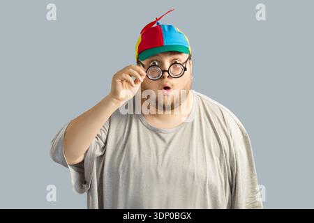 Surprised overweight man in colorful propeller cap and round glasses, comic Stock Photo