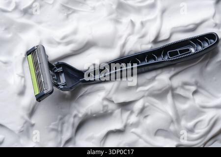 Close up of upper part of razor submerged in thick white foam. Detailed texture of plastic and foam Stock Photo