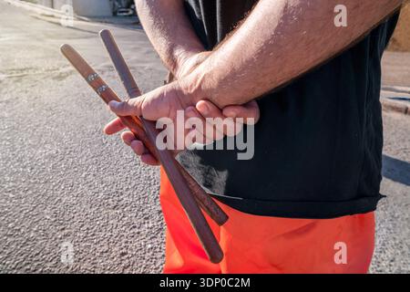 Man holding wooden drumsticks behind his back, preparing for music performance Stock Photo