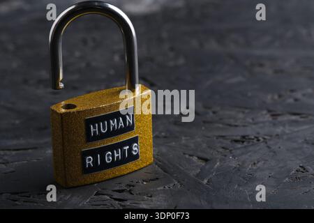 Open golden padlock with Human Rights sign on dark background, conceptual image of freedom and justice Stock Photo
