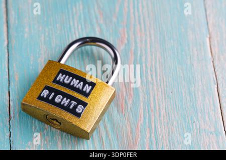 Closed golden padlock with Human Rights label on blue wood. Concept of legal protection or restriction Stock Photo