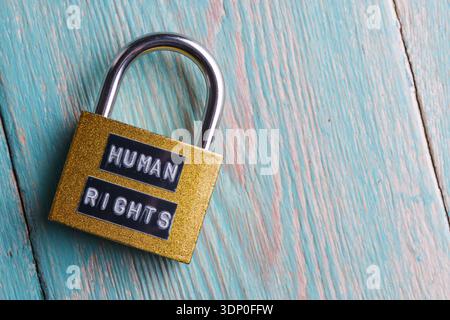 Padlock with Human Rights sign on textured wooden surface. Symbol of social justice and law Stock Photo