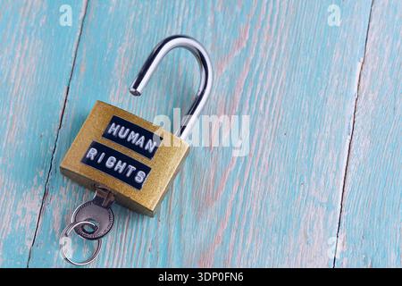Open golden padlock with Human Rights text and key on turquoise wooden background Stock Photo