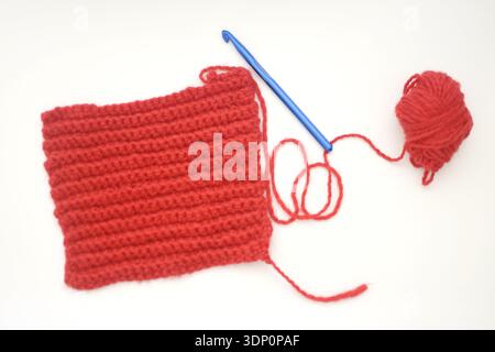 Red Crochet Piece with Blue Crochet Hook on Wooden Table, Top View Flat Lay Stock Photo