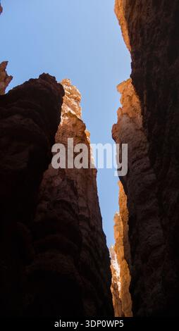 A narrow opening reveals a slice of sky above the canyon walls. The composition emphasizes the scale and enclosure of the stone corridors. Stock Photo