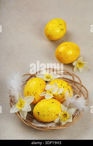 Vertical composition of yellow Easter eggs with daffodils and feathers Stock Photo