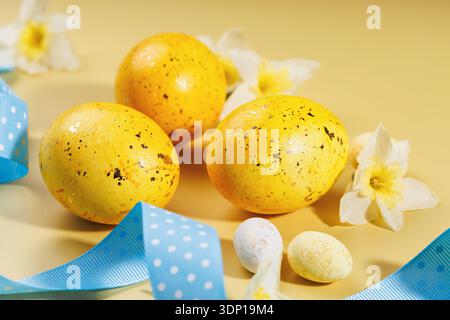 Speckled Easter eggs and spring flowers on beige surface Stock Photo