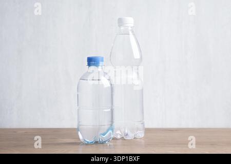 Water bottles of different sizes on wooden table Stock Photo