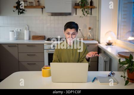 Positive confident senior businesswoman talking online by video call on laptop from cozy home office Stock Photo