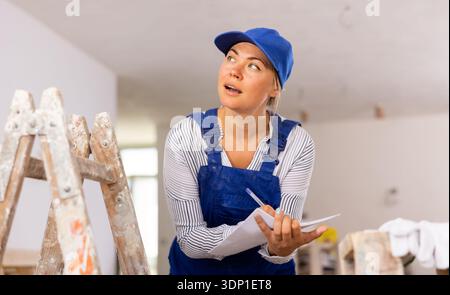 Female contractor taking notes while planning works at building site Stock Photo
