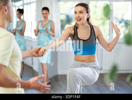 Cheerful woman practicing vigorous swing with man at dance class Stock Photo