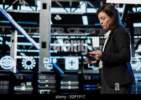 Augmented reality upgraded server farm software developer optimizing equipment with tablet. Data center employee updating electronics system with device, VFX compositing futuristic technology concept Stock Photo