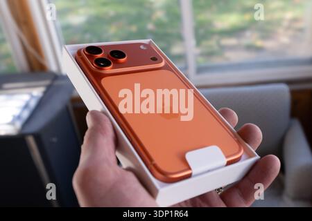 Iphone 17 Pro Max in cosmic orange is new and in packaging illustrating the sleek new design, color and new camera configuration of the latest model Stock Photo