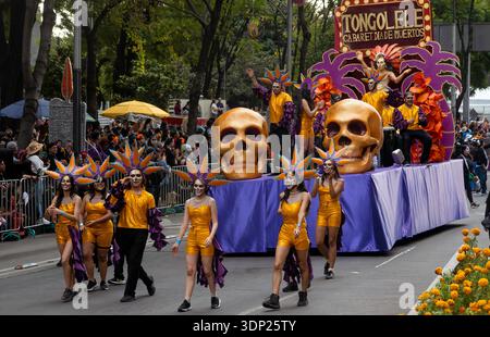 People walk and ride on a float with giant skulls during a Day of the Dead parade on Paseo de la Reforma Avenue in Mexico City, Mexico Stock Photo
