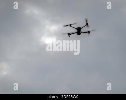 Quadcopter drone flying against a background of  grey clouds with copy space Stock Photo