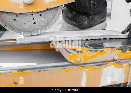 tiling work.Cutting tiles with a construction saw. Mechanical cutter for cutting hard materials.Construction equipment and tools with saws  Stock Photo