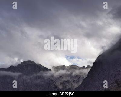 Dark, dramatic clouds over jagged mountain peaks creating a majestic scene, Peaks of the Balkans, hiking in the Albanian Alps National Park, Albania Stock Photo
