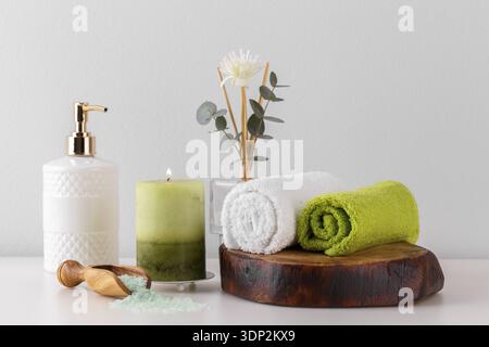 Health care and spa items on white shelf, green towels candle soap and salt Stock Photo