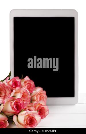 Tablet and bouquet of pink roses on white background. Space for text Stock Photo
