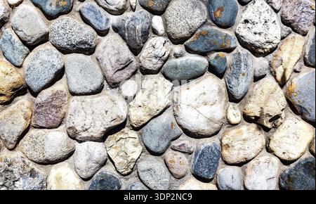 Rough stone wall as creative background texture. Natural stones masonry with uneven seams. Stone wall background Stock Photo