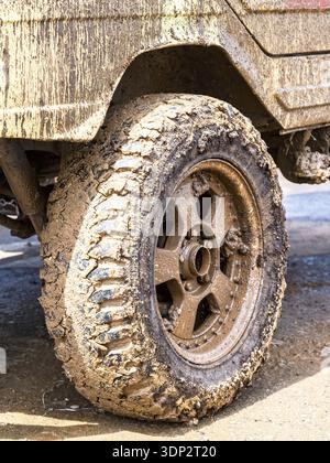 Extremely dirty off-road car wheel after driving heavy off-road in the rain Stock Photo