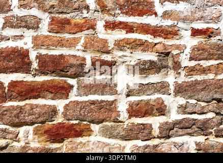 Ancient weathered rough stone wall as creative background. Grunge brick wall texture background. Wall of the fortress is made of stone of different si Stock Photo