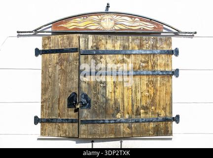 Closed old window with wooden shutters, forged metal hinges and padlock close up Stock Photo