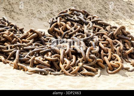 Huge rusty anchor chains of an old ship on the sand beach Stock Photo