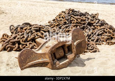 Rusty anchor chain with ship anchor of an old ship on the sand beach Stock Photo