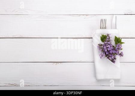 Spring festive table setting with vintage cutlery and lilac flowers on white wooden table, copy space flat lay Stock Photo