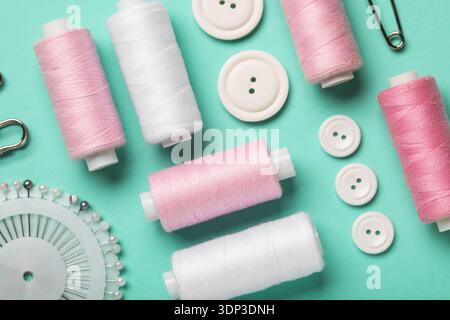 Composition with thread spools, ball pins and buttons on mint background, closeup Stock Photo