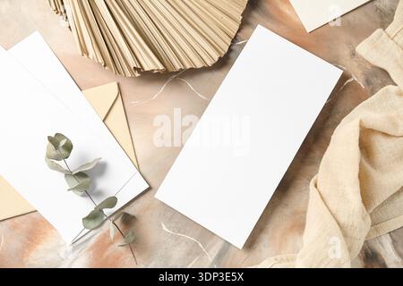Envelope with blank cards, eucalyptus branch, dried palm leaf and fabric on grunge background Stock Photo