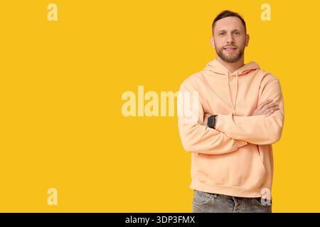 Stylish young man in hoodie on yellow background Stock Photo