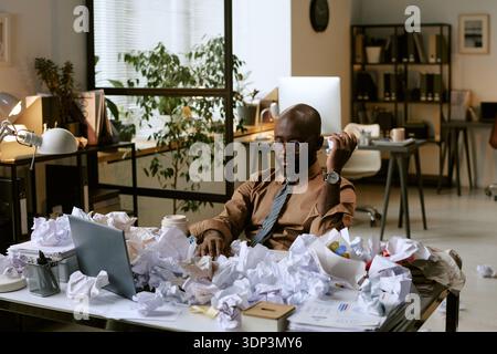 Black Man Sitting at Desk Handling Stressful Office Workload Stock Photo