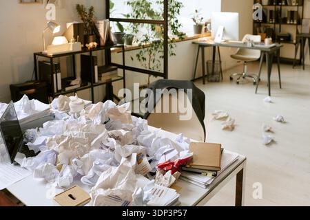 Messy Office Desk Covered with Crumpled Papers Representing Workplace Stress Stock Photo