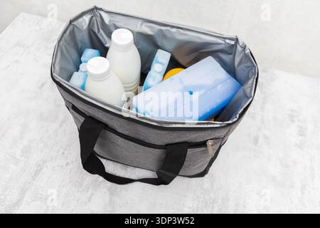 Gray insulated bag open. Inside: white bottles, blue cold packs. System for food, drink temperature control. Ideal for outdoor use, travel, grocery. Stock Photo