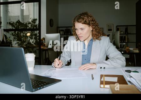 Woman Analyzing Financial Documents While Working in Office Stock Photo