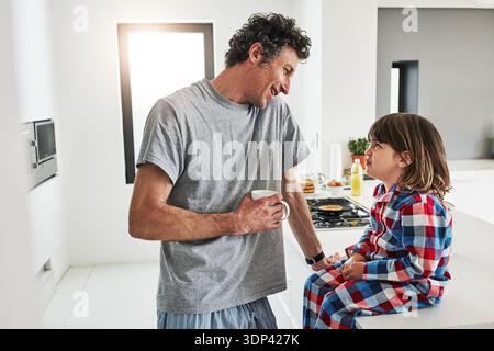 Home, talking and father with son in kitchen, love and start day with morning routine. Apartment, family and parent with child, dad and conversation Stock Photo