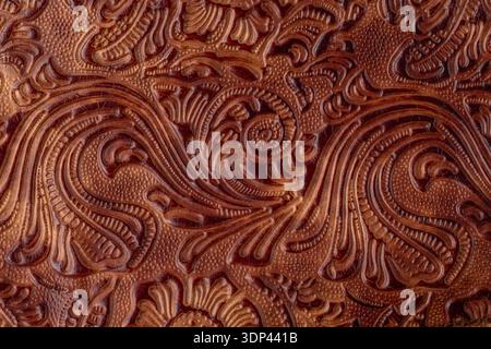 Dark brown red old cracked  leather with floral print. Sample of rough leather with ornament. Vintage style. Retro leather background. Stock Photo