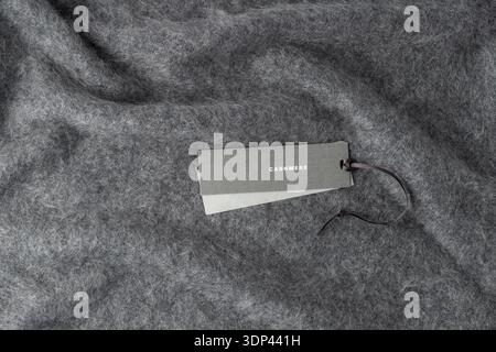 Paper tag with word cashmere on dark grey luxury pure cashmere background with copy space. Fluffy brushed cashmere texture. Stock Photo