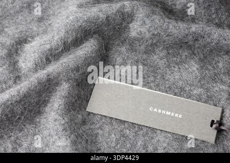 Paper tag with word cashmere on dark grey luxury pure cashmere background with copy space. Fluffy brushed cashmere texture. Stock Photo