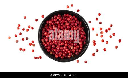 Pink peppercorn  pepperberry  in black bowl flying isolated on white background. Aromatic spicy ingredient for cuisine. Seasoning card. Stock Photo