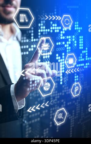 Businessman interacts with digital interface and data icons in an office setting Stock Photo